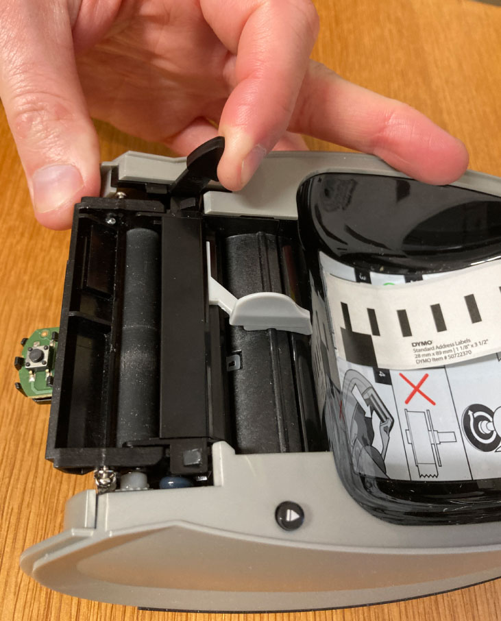Pull the left lever forward to manually remove labels from the Dymo 450 printer